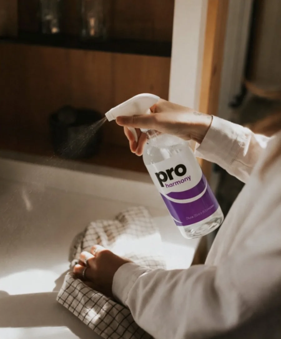 Cleaner wiping down a benchtop with spray and cloth